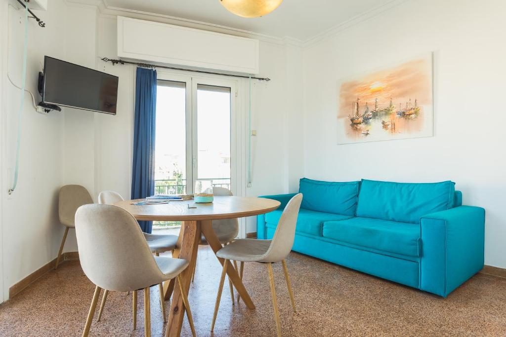 アテネにあるSuper Paradise Apartmentsのリビングルーム(青いソファ、テーブル、椅子付)