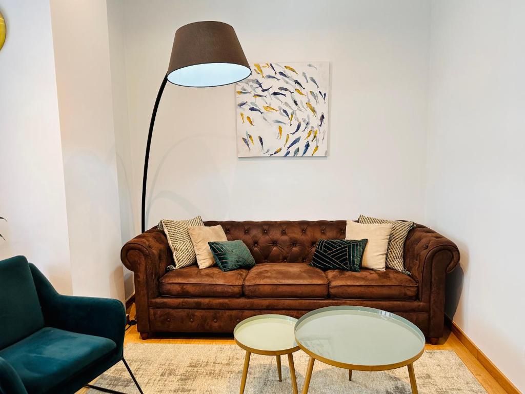 ein Wohnzimmer mit einem braunen Sofa und 2 Tischen in der Unterkunft Vaibar Apartaments en el centro de Vigo entorno plaza de Compostela in Vigo