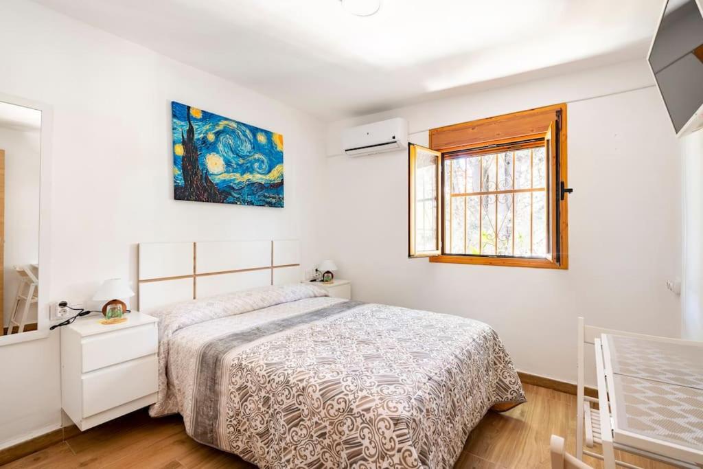 a white bedroom with a bed and a window at El Remanso in Seville