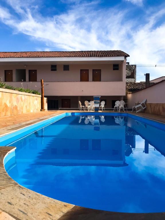 a large blue swimming pool in front of a house at Pousada Serra Branca in São Thomé das Letras