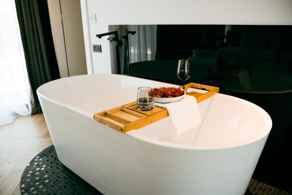 a bath tub with a glass of wine and a bowl of fruit at Evo Residence Panoramic in Cluj-Napoca