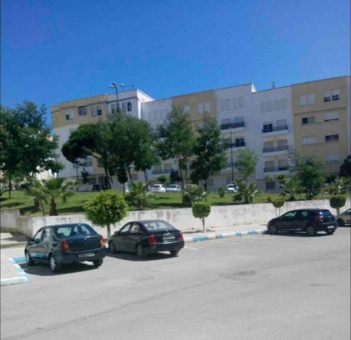 tres autos estacionados en un estacionamiento frente a un edificio en Grand appartement 1 chambre en Tánger