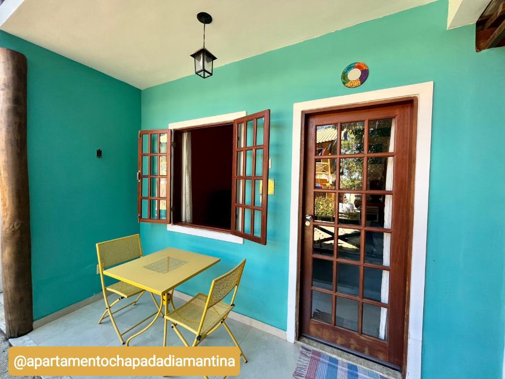 una mesa y sillas en una habitación con una pared azul en Apartamento Chapada Diamantina, en Lençóis