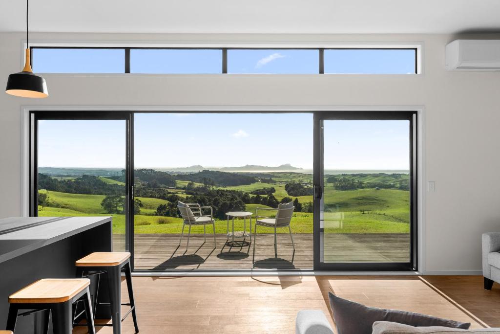 a living room with large glass doors and a view of the countryside at Modern Sanctuary - Waipu Holiday Home in Waipu Cove