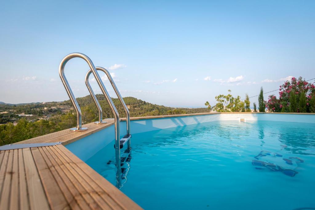 a swimming pool with a wooden deck and blue water at LES NINES in Calpe