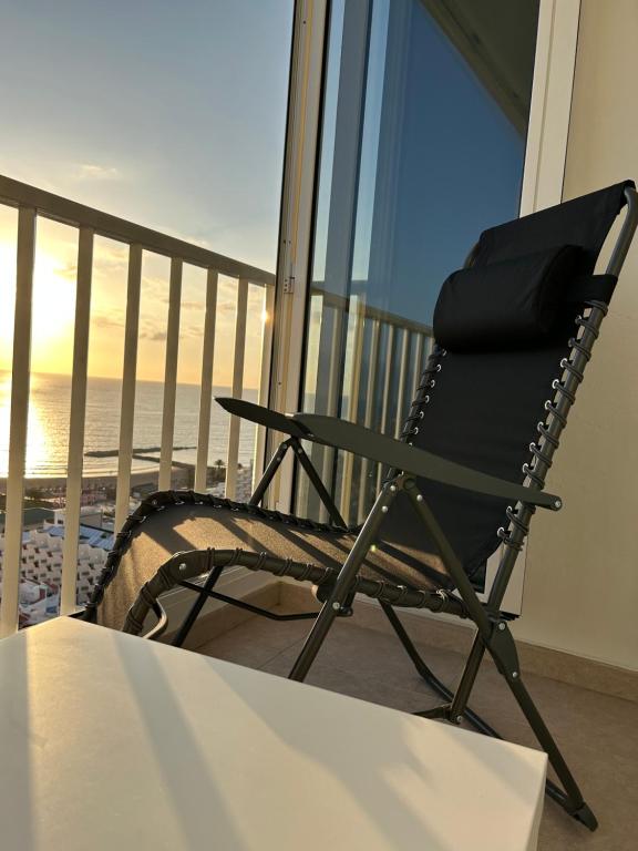 een zwarte schommelstoel op een balkon met uitzicht op de oceaan bij Atlantic Sunset Floor - Las Americas in Playa de las Americas