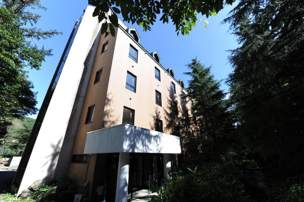 a large brick building with trees in front of it at Tabist More Resort Nire no Ki Hakuba in Hakuba