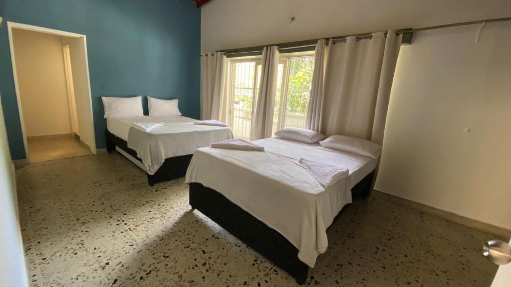 een kamer met 2 bedden en een raam bij Aparta Hotel Mediterráneo Estadio in Medellín