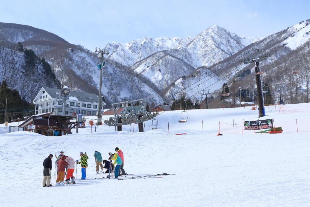 un gruppo di persone in piedi sulla neve vicino a un impianto di risalita di Tabist Condominium Hakuba Goryu a Hakuba