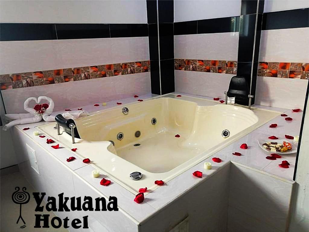 a white bath tub with red rose petals around it at Hotel Yakuana in Puerto López