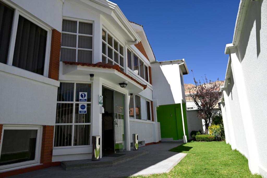 a white building with a green door and grass at Bolivian Rooms & Suites (Zona Sur) in La Paz
