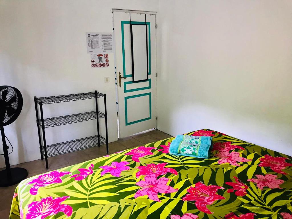 Schlafzimmer mit einem Bett mit grüner und rosafarbener Decke in der Unterkunft CHEZ ANIAKI in Nuku Hiva