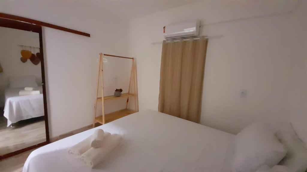 een slaapkamer met een wit bed en een spiegel bij Quarto Dani in Jericoacoara