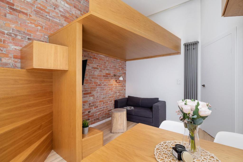 ein Wohnzimmer mit einem Tisch und einer Ziegelwand in der Unterkunft Apartment with Mezzanine - Ariańska 14 by Renters in Krakau