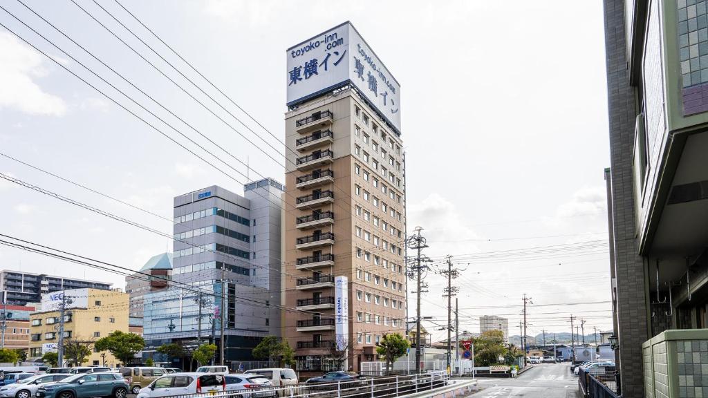 Un palazzo alto con un cartello sopra. di Toyoko Inn Kakegawa eki Shinkansen Minami guchi a Kakegawa