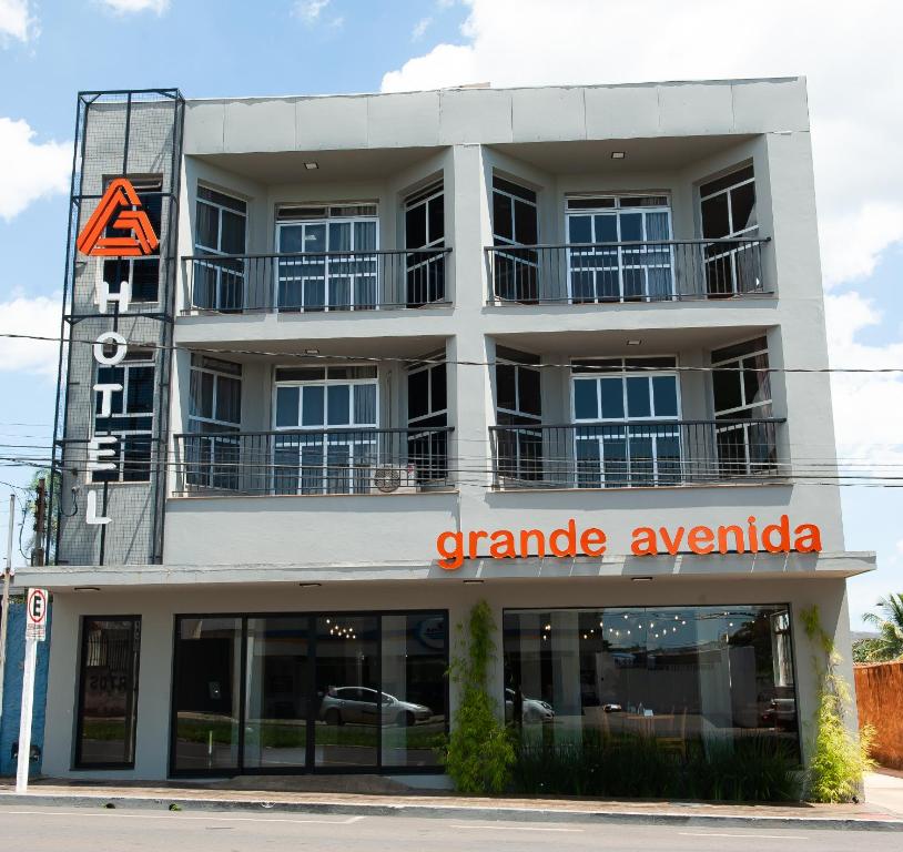 a large white building with a garage avida at Grande Avenida Hotel in Patrocínio