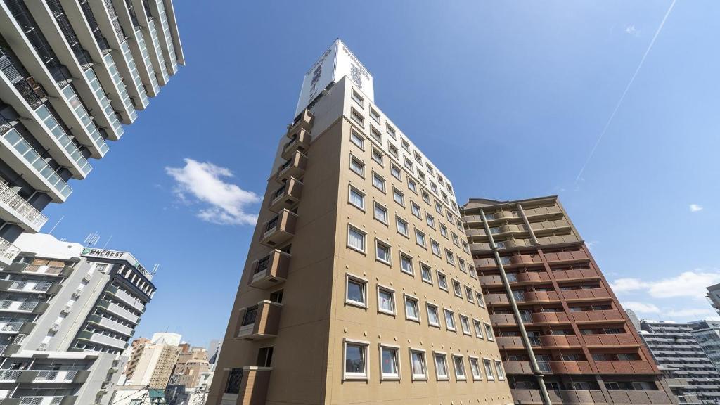 un edificio alto en medio de algunos edificios en Toyoko Inn Fukuoka Tenjin, en Fukuoka