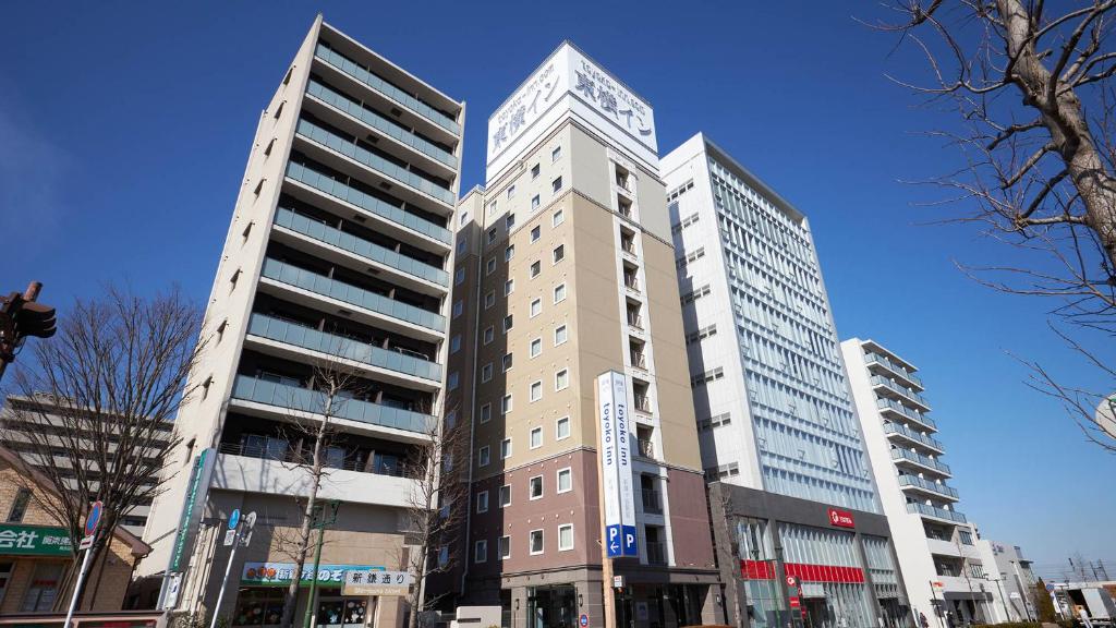 twee hoge gebouwen in een stadsstraat bij Toyoko Inn Chiba Shin kamagaya Ekimae in Kamagaya
