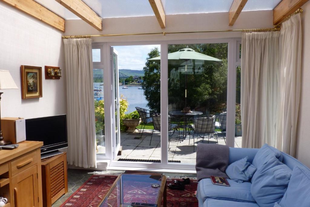 sala de estar con sofá y puerta corredera de cristal en Achnamara Apartment, en Connel