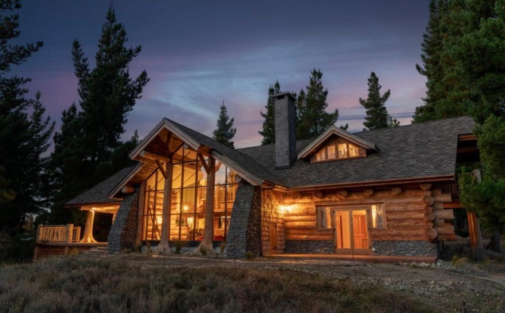 Fairytale Log Cabin - Homewood Forest Retreat في ألكسندرا: منزل خشبي مع واجهة مضاءة في الليل