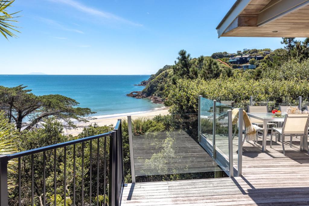 einen Balkon mit einem Tisch und Strandblick in der Unterkunft Tawa Cottage - Coast & Country in Oneroa