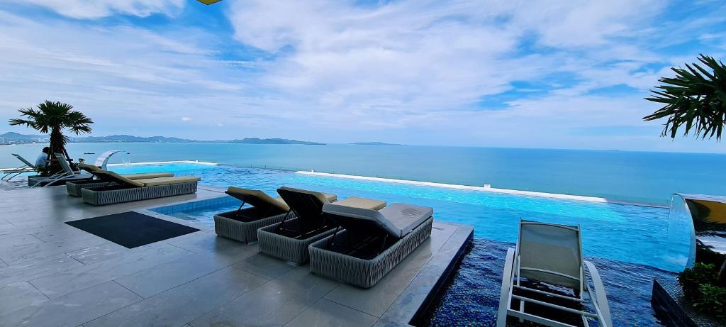 una piscina con divani e sedie accanto all'acqua di Seaview Beachfront Skypool Rooftop Copacabana Jomtien Condo a Jomtien Beach