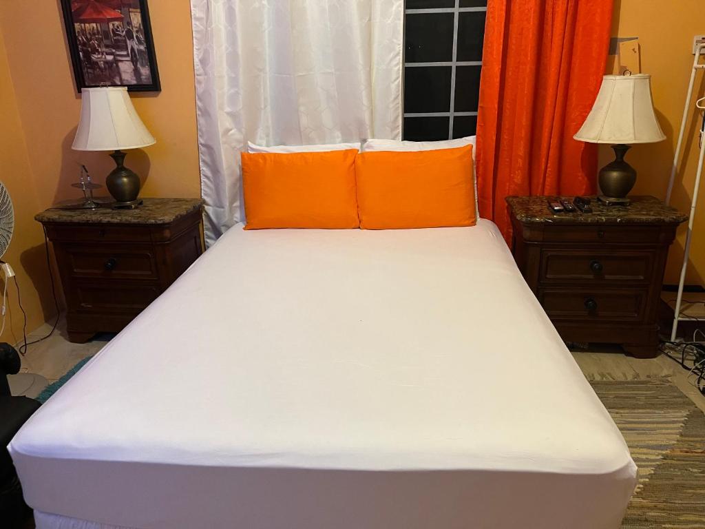 a large bed with orange pillows and two lamps at Cool Breeze Mobay in Montego Bay