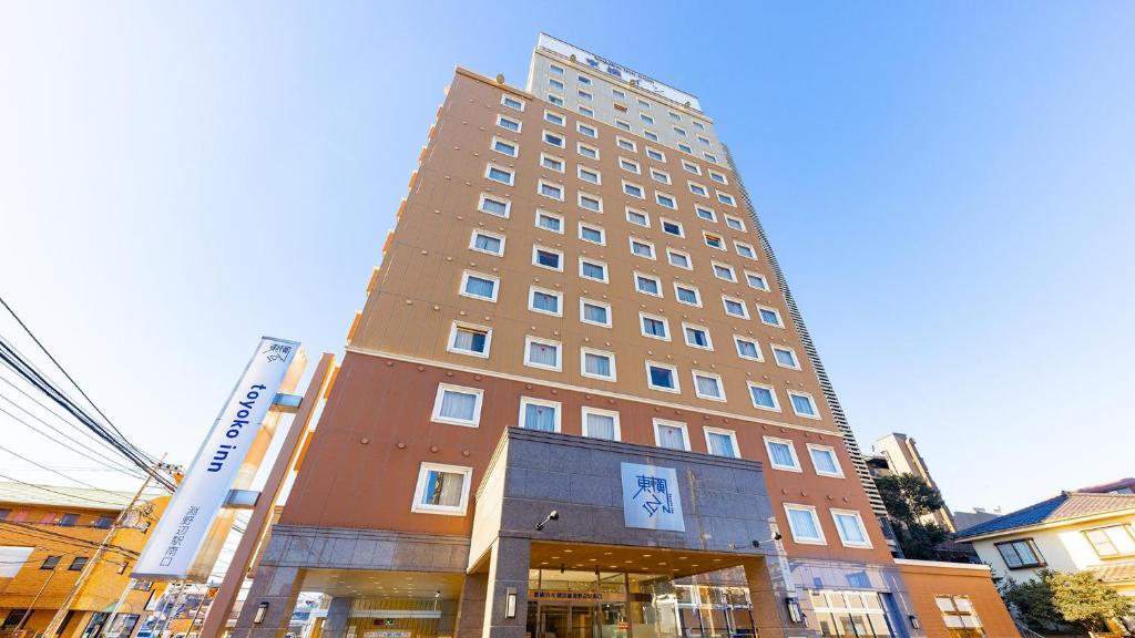 wysoki budynek z znakiem przed nim w obiekcie Toyoko Inn Yokohama-sen Fuchinobe-eki Minami-guchi w mieście Sagamihara