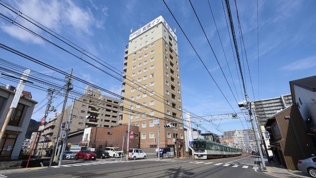 um edifício alto numa rua da cidade com um autocarro em Toyoko Inn Kyoto Biwako Otsu em Otsu