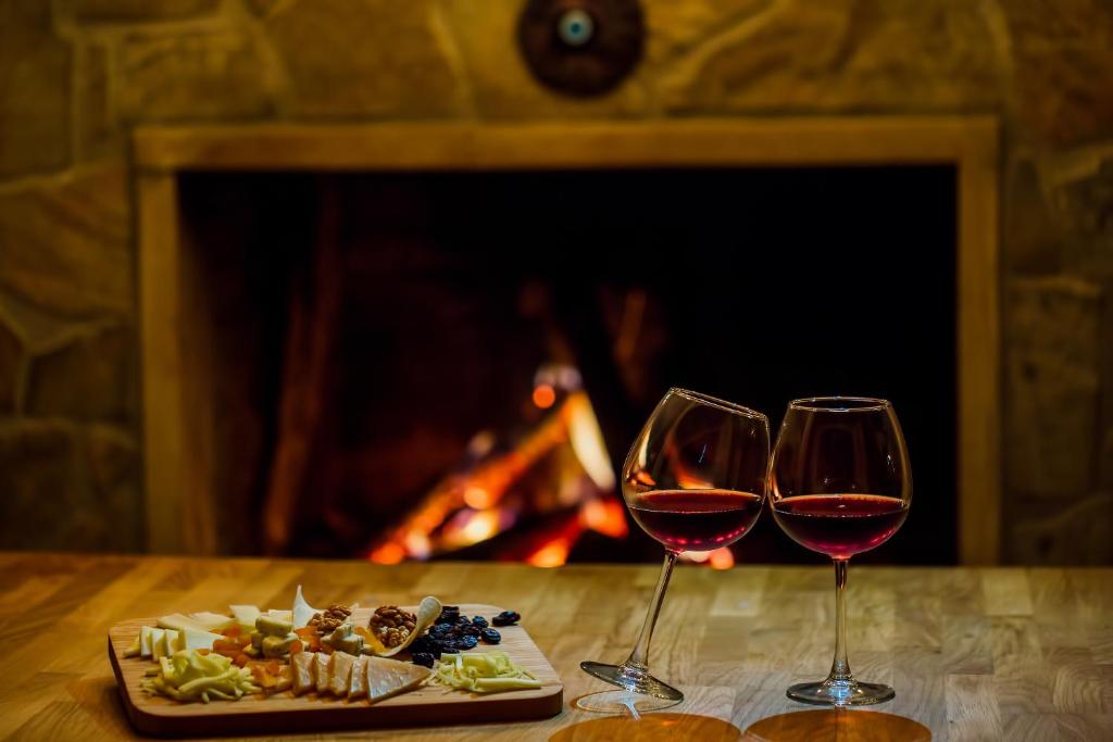 two glasses of wine and a plate of food on a table with a fireplace at Park Mandalin Hotel - Adult only in Ağva