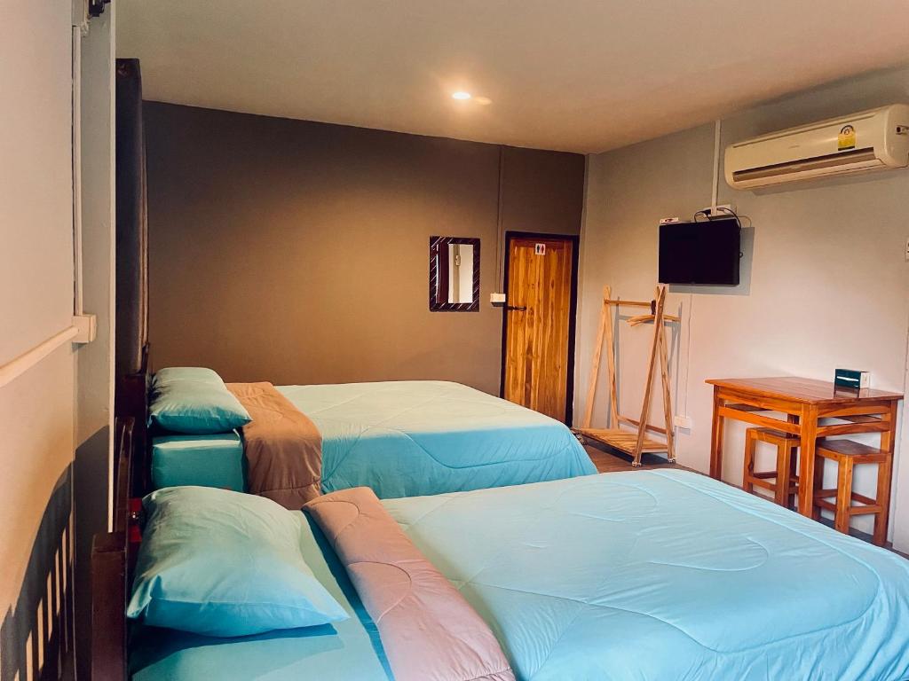 a room with three beds and a table and a television at Chiang Dao Hostel in Chiang Dao