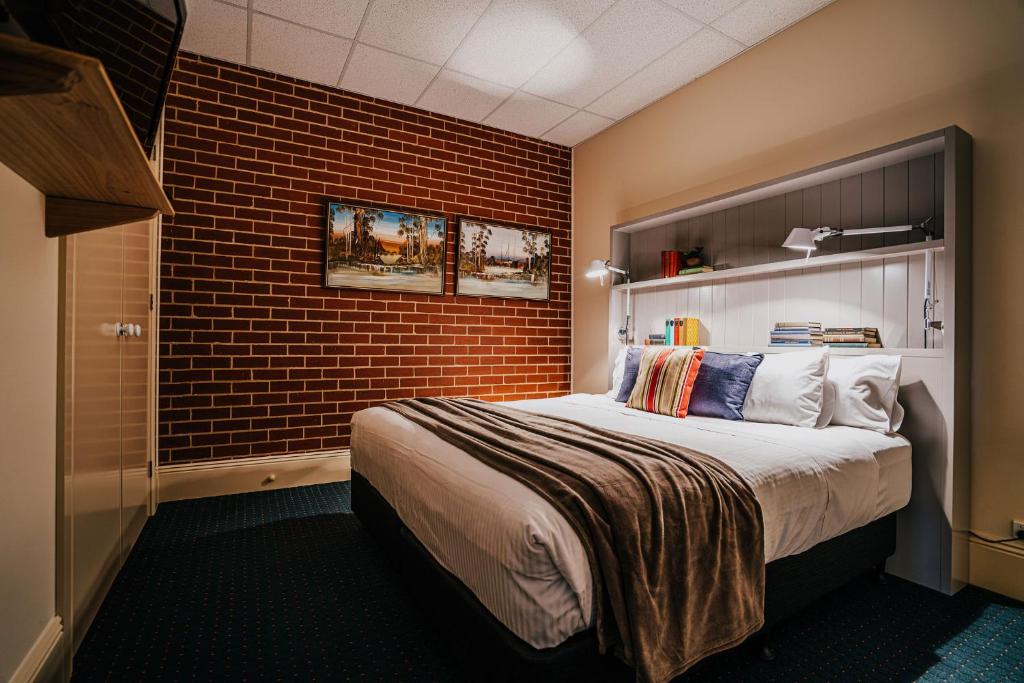 une chambre d'hôtel avec un lit et un mur en briques dans l'établissement Mister Rice, à Castlemaine