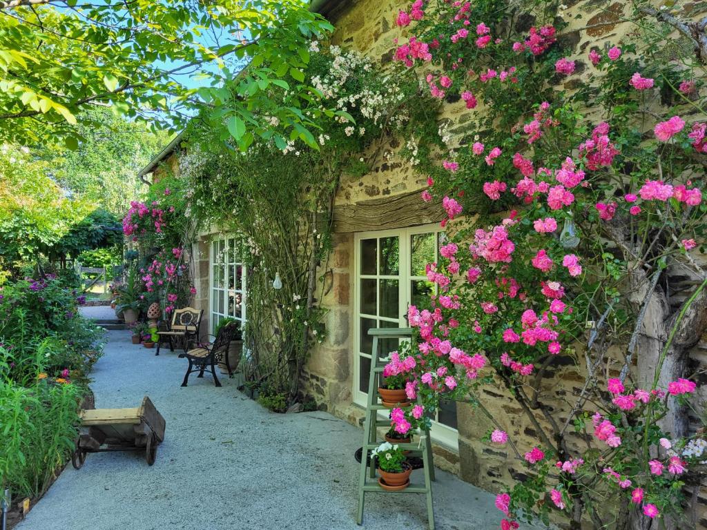 un edificio con fiori rosa sul lato di Les Causeries du Monde a Chamboulive