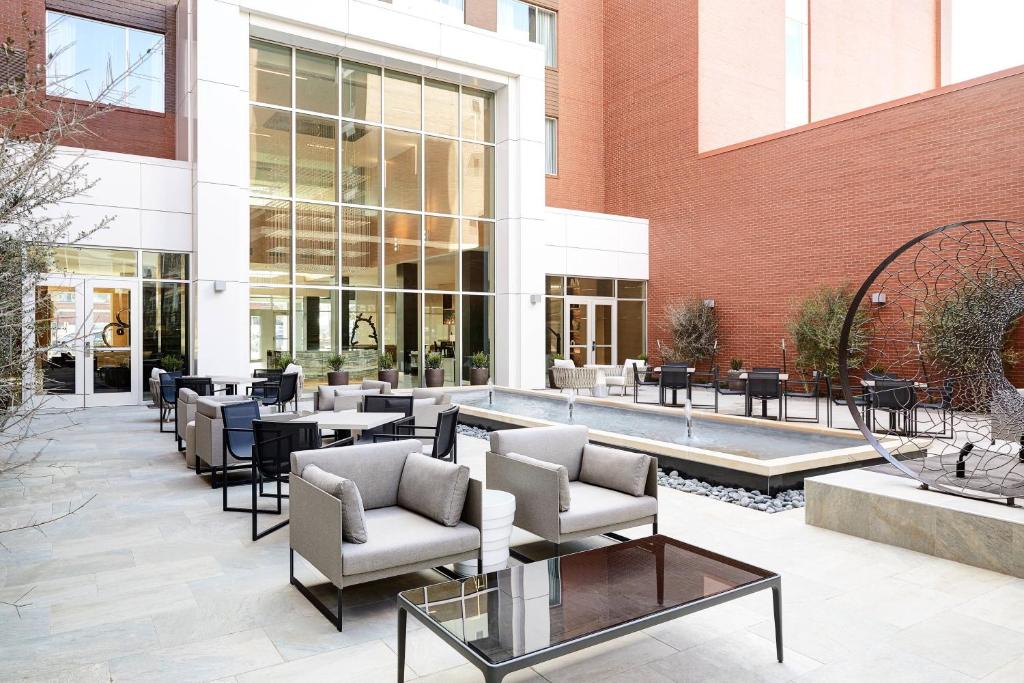 un patio con tavoli e sedie di fronte a un edificio di AC Hotel by Marriott Oklahoma City Bricktown a Oklahoma City