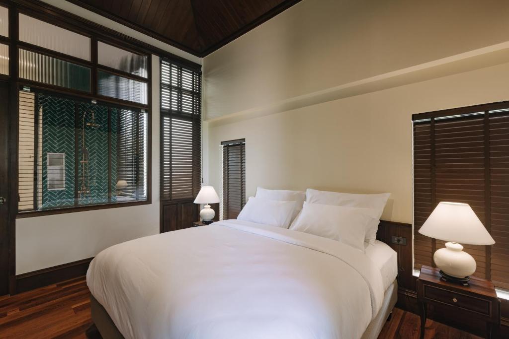 a bedroom with a large white bed with two lamps at Coucou Hotel in Chiang Mai
