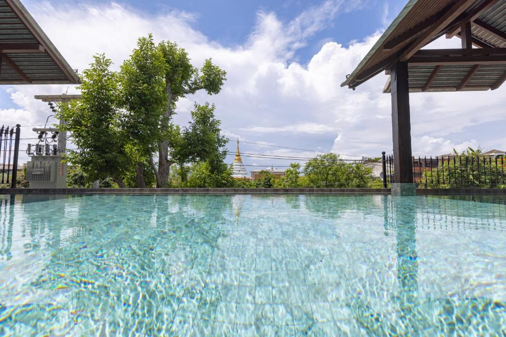 Clear blue pool water fills the foreground, with covered poolside structures and a distant temple-like view.