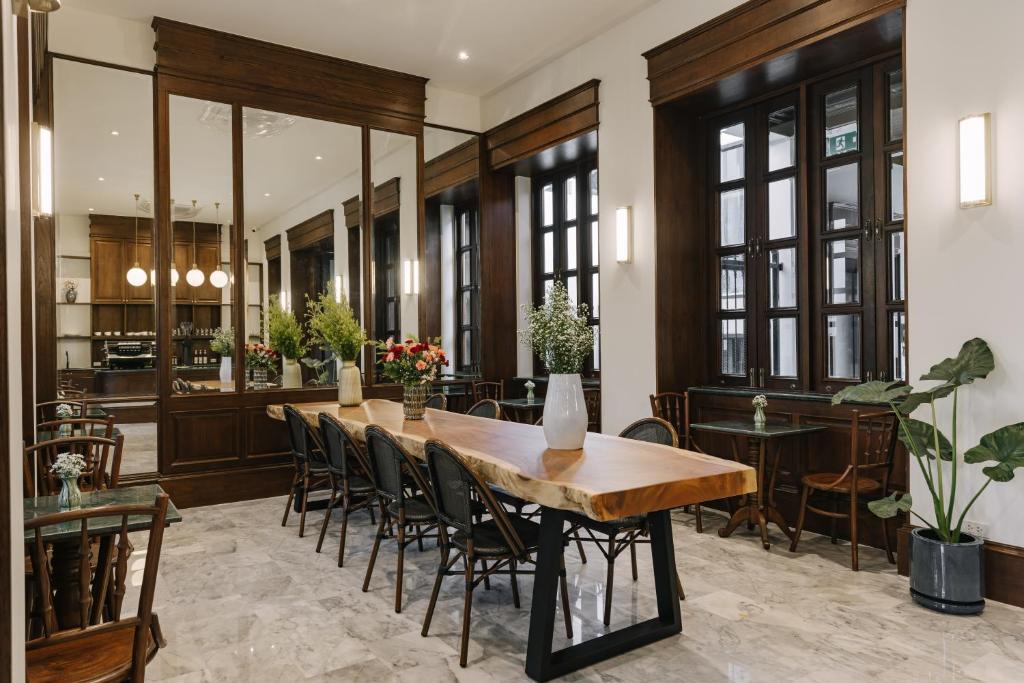 A bright dining room combines a long communal table with smaller tables beside tall windows.