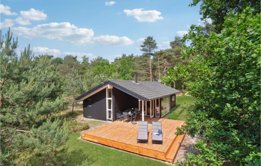 a small black cabin in the woods with a deck at Stunning Home In Aakirkeby With 3 Bedrooms And Wifi in Vester Sømarken