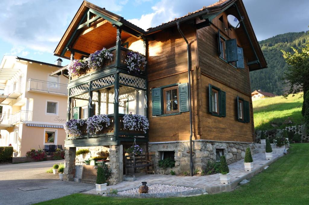 ein großes Holzhaus mit einem Brunnen davor in der Unterkunft Ferienhaus Sapplerhof in Millstatt