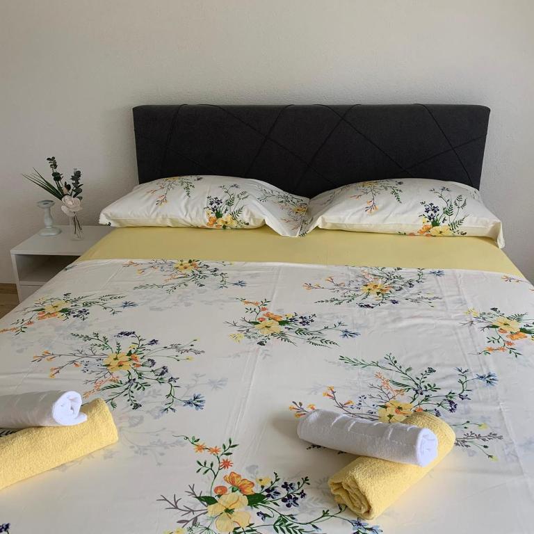 a bed with a floral bedspread and two pillows on it at Apartman TESA in Sanski most