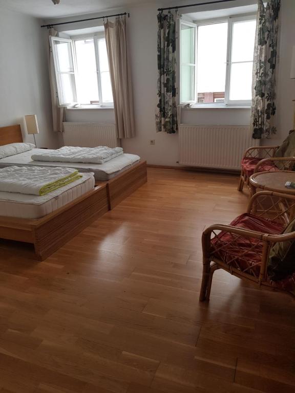 a bedroom with two beds and a chair and two windows at Hostel in der Altstadt NepomukB&B in Innsbruck