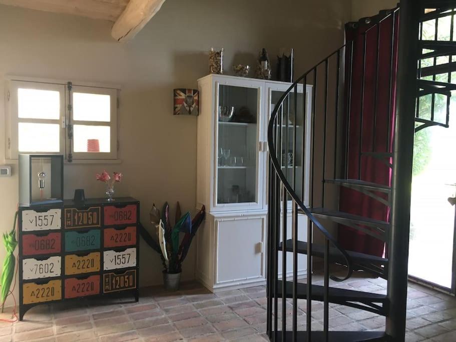 a room with a staircase and a cabinet with books at Gite des amis Domaine de Mas Caron in Caromb