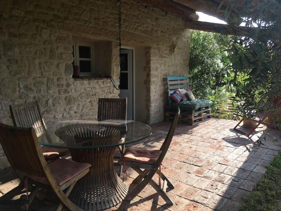 a patio with a glass table and some chairs at Gite des amis Domaine de Mas Caron in Caromb