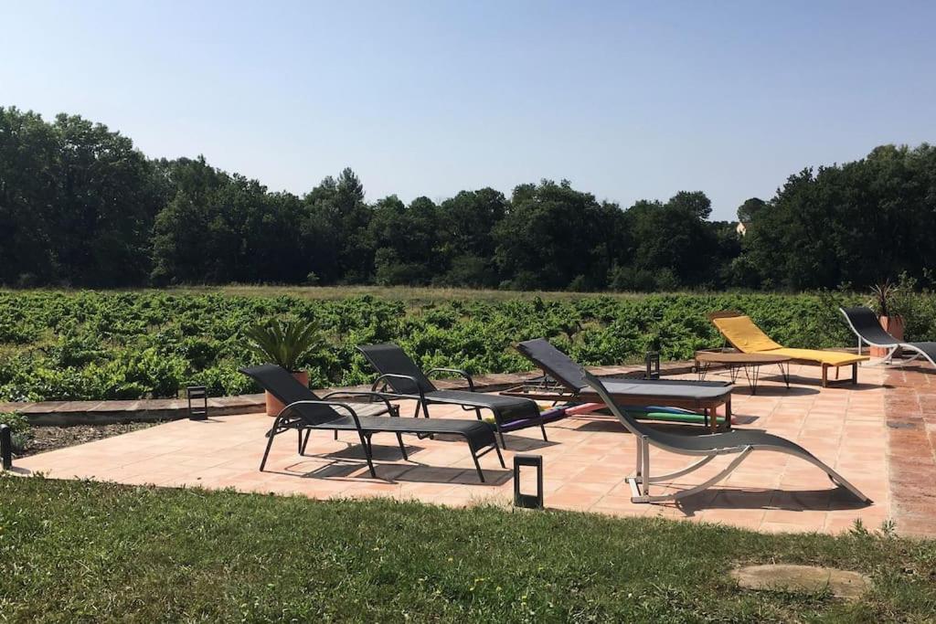 a group of chairs sitting on a patio in front of a field at Gite des amis Domaine de Mas Caron in Caromb