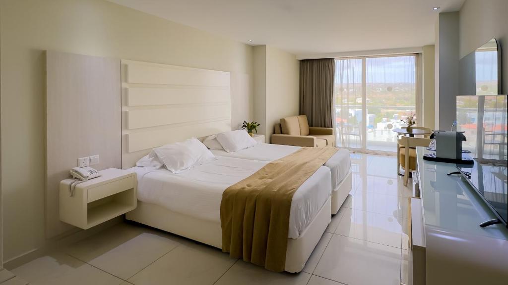 a hotel room with a large bed and a balcony at Tasia Maris Beach Hotel - Adults Only in Ayia Napa