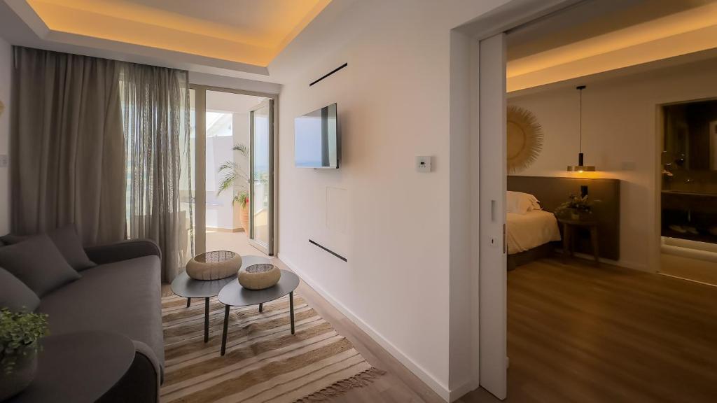 a living room with a couch and a room with a bed at Tasia Maris Beach Hotel - Adults Only in Ayia Napa
