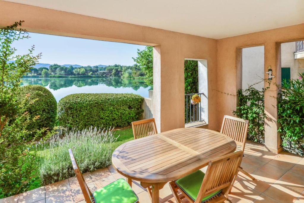 un patio avec une table et des chaises et une vue sur un lac dans l'établissement Village Pont Royal en Provence - maeva Home - Appartement 2 pièces 5 personnes Confort MAE-2264, à Mallemort