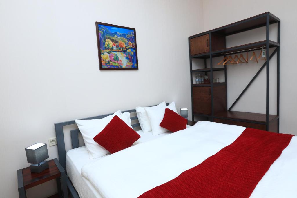 1 dormitorio con 2 camas y almohadas rojas en Syune Mini Hotel en Gyumri