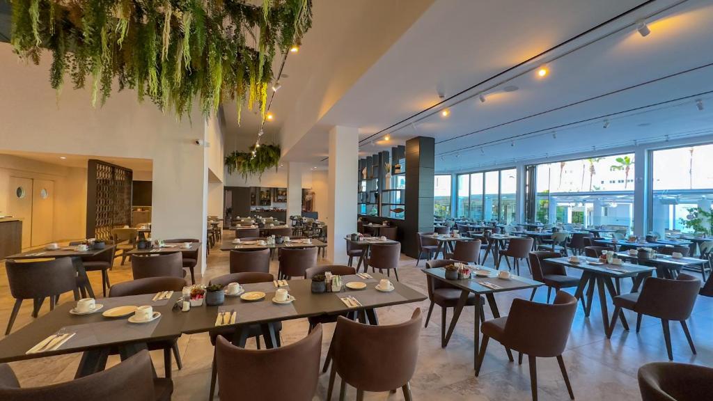 a restaurant with tables and chairs and windows at Tasia Maris Beach Hotel - Adults Only in Ayia Napa