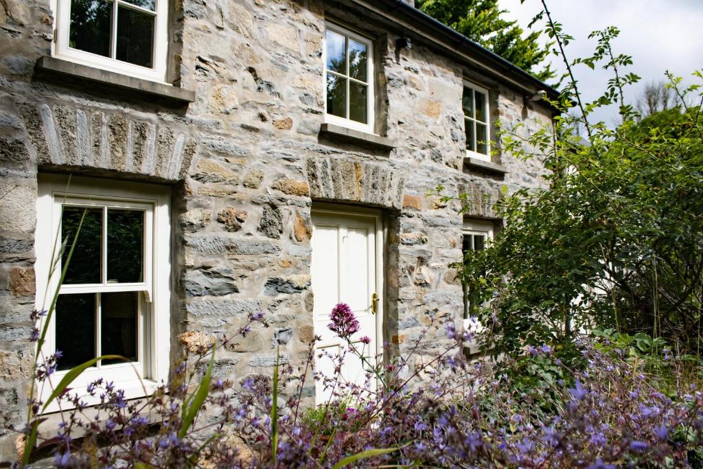 an old stone house with white windows and purple flowers at Minafon in Newport